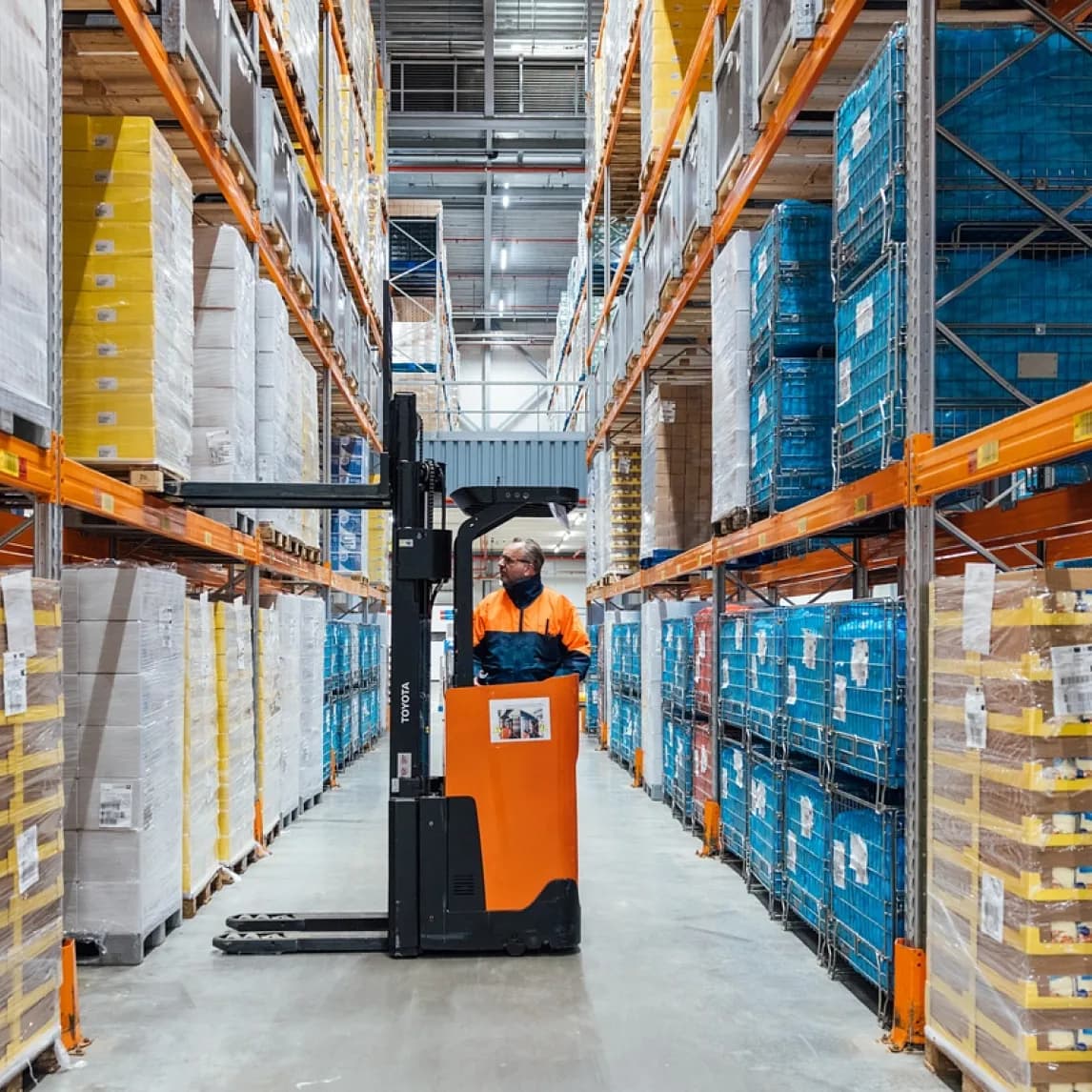 A worker moving pallets in a wholesale warehouse